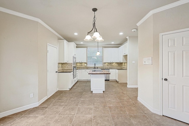 kitchen featuring appliances with stainless steel finishes, white cabinetry, ornamental molding, and decorative backsplash