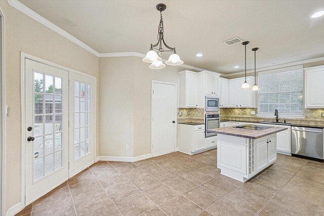 kitchen featuring decorative backsplash, a center island, white cabinets, and appliances with stainless steel finishes