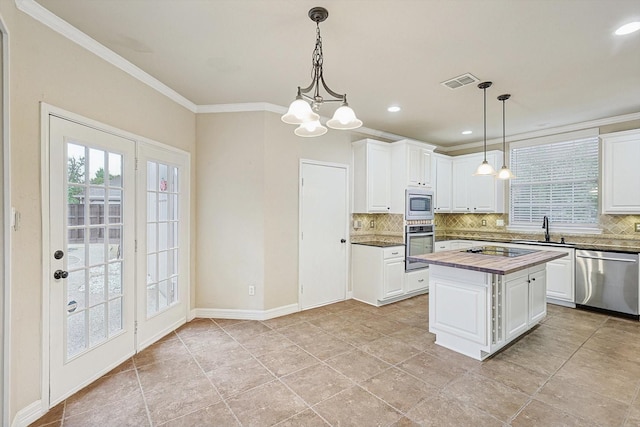 kitchen featuring butcher block counters, a sink, visible vents, appliances with stainless steel finishes, and decorative backsplash