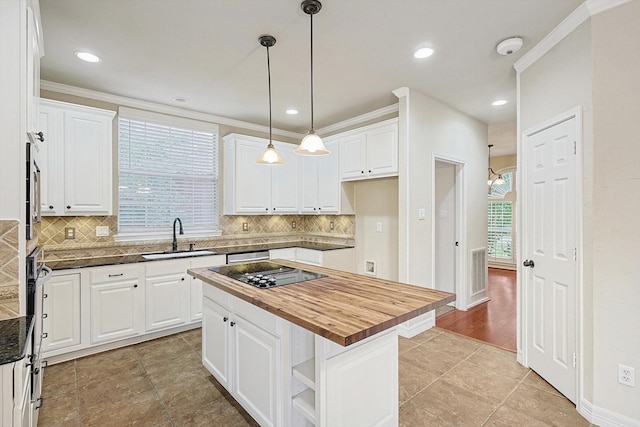 kitchen featuring wooden counters, a sink, white cabinetry, and crown molding