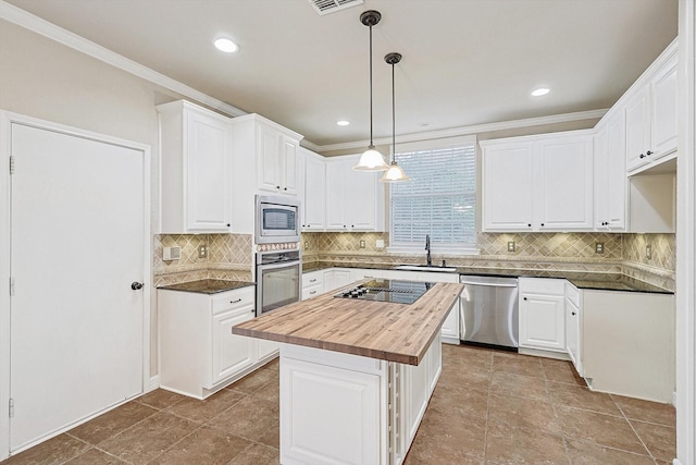 kitchen featuring appliances with stainless steel finishes, butcher block countertops, a sink, and white cabinets