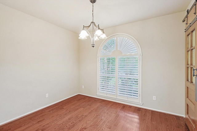 unfurnished room with a notable chandelier, baseboards, and wood finished floors