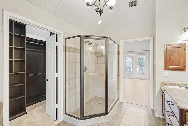 full bathroom with vanity, vaulted ceiling, french doors, a stall shower, and an inviting chandelier