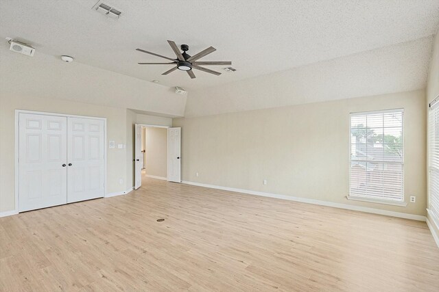 interior space featuring ceiling fan, lofted ceiling, a textured ceiling, and light wood-type flooring