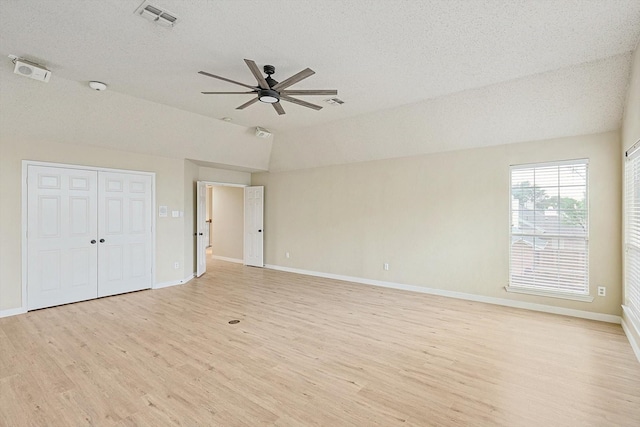 empty room featuring baseboards, visible vents, a ceiling fan, lofted ceiling, and light wood-style flooring