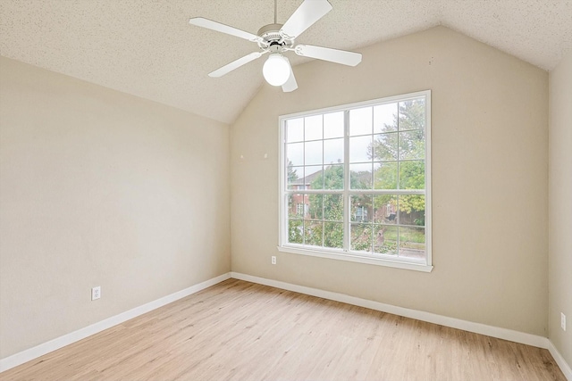 unfurnished room with baseboards, a ceiling fan, wood finished floors, vaulted ceiling, and a textured ceiling