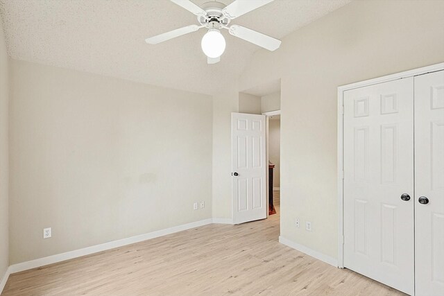 empty room featuring lofted ceiling, ceiling fan, a textured ceiling, and light wood-type flooring