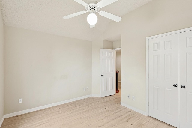 unfurnished bedroom with baseboards, lofted ceiling, ceiling fan, light wood-style floors, and a closet