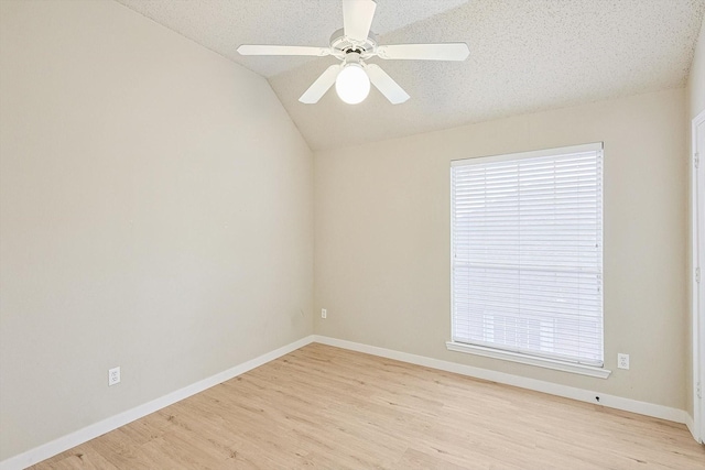 unfurnished room featuring light wood finished floors, vaulted ceiling, ceiling fan, a textured ceiling, and baseboards