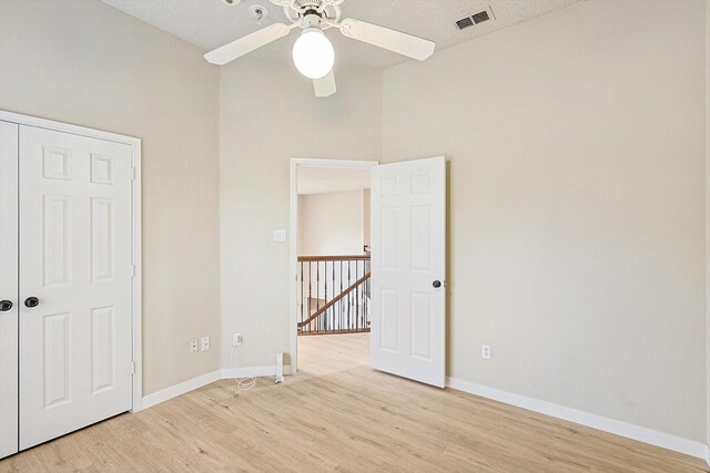 spare room with lofted ceiling, ceiling fan, light hardwood / wood-style floors, and a textured ceiling