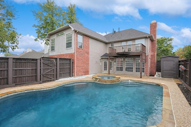 view of swimming pool with an outbuilding, a fenced backyard, a pool with connected hot tub, a wooden deck, and a shed