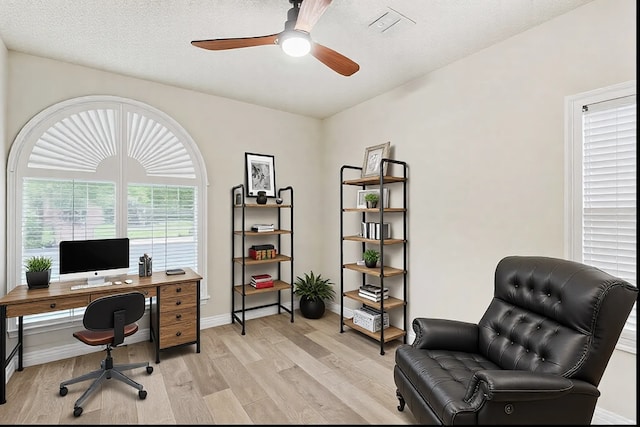 office with a textured ceiling, ceiling fan, light wood-style flooring, and baseboards