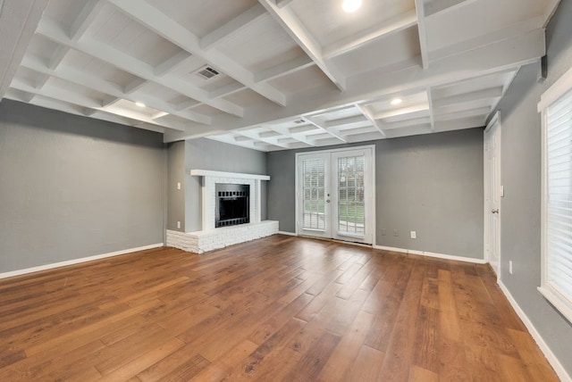 unfurnished living room featuring a brick fireplace, beamed ceiling, hardwood / wood-style flooring, and coffered ceiling