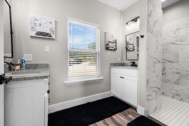 bathroom featuring vanity, hardwood / wood-style flooring, tiled shower, and plenty of natural light