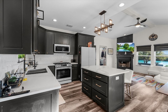 kitchen featuring dark hardwood / wood-style flooring, a kitchen island, vaulted ceiling with beams, and stainless steel appliances