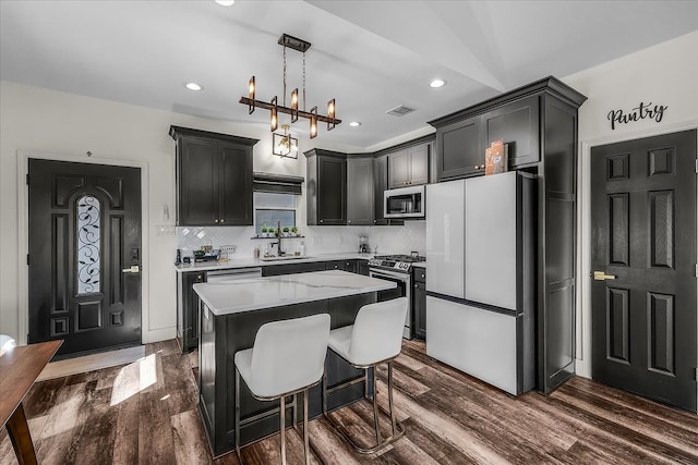 kitchen with stainless steel appliances, dark hardwood / wood-style flooring, a center island, decorative backsplash, and pendant lighting