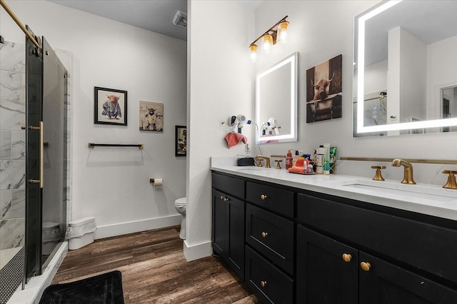 bathroom with hardwood / wood-style floors, a shower with door, vanity, and toilet