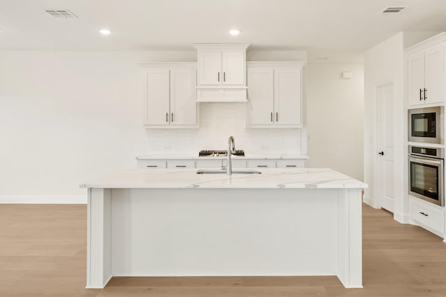 kitchen with light wood-style floors, visible vents, decorative backsplash, and oven