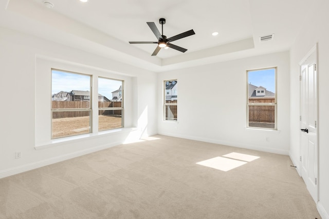 spare room with light carpet, baseboards, visible vents, and a raised ceiling