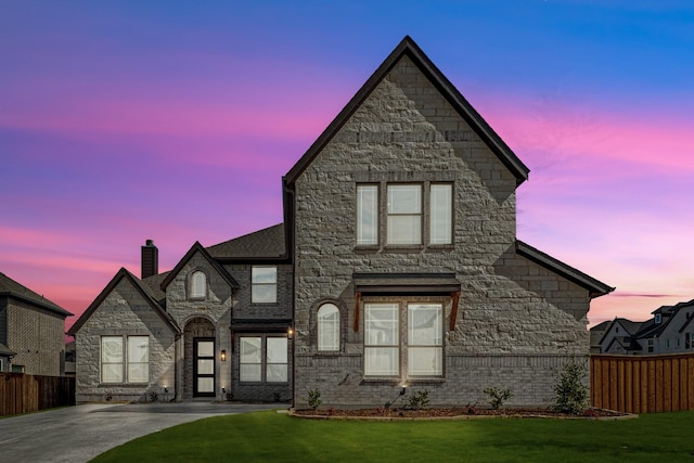 view of front of property with brick siding, fence, and a front lawn