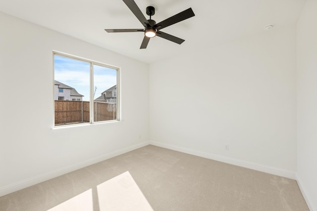 unfurnished room featuring a ceiling fan, light carpet, and baseboards