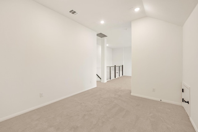 spare room with visible vents, vaulted ceiling, light carpet, and baseboards