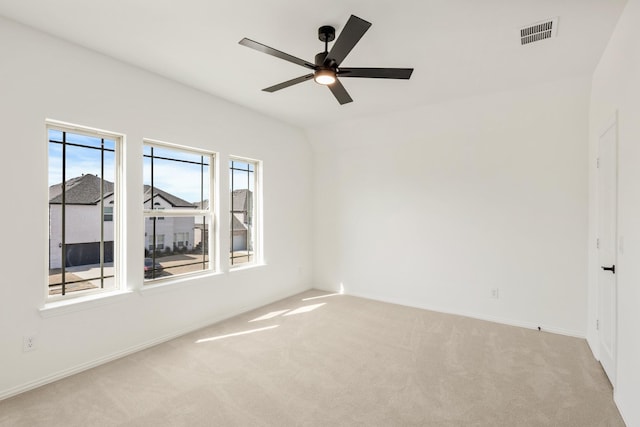 spare room featuring light colored carpet, ceiling fan, visible vents, and baseboards