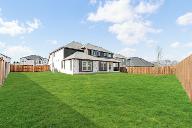 back of property featuring a fenced backyard, a lawn, and brick siding