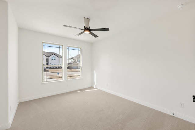 empty room featuring carpet floors, a ceiling fan, and baseboards