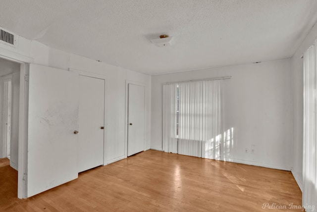 unfurnished bedroom featuring a textured ceiling and light hardwood / wood-style flooring