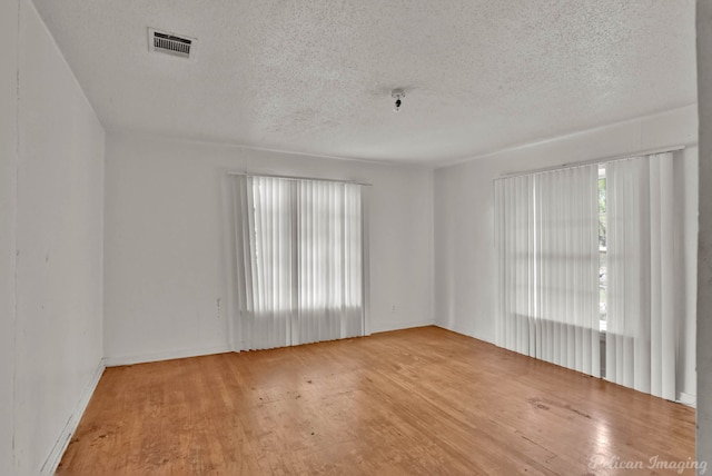 unfurnished room with wood-type flooring and a textured ceiling