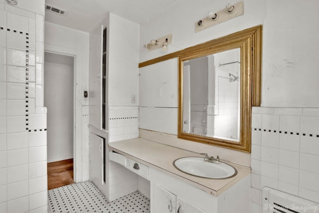 bathroom with tile walls, tile patterned flooring, and vanity