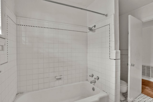 bathroom with toilet, tiled shower / bath, and hardwood / wood-style flooring