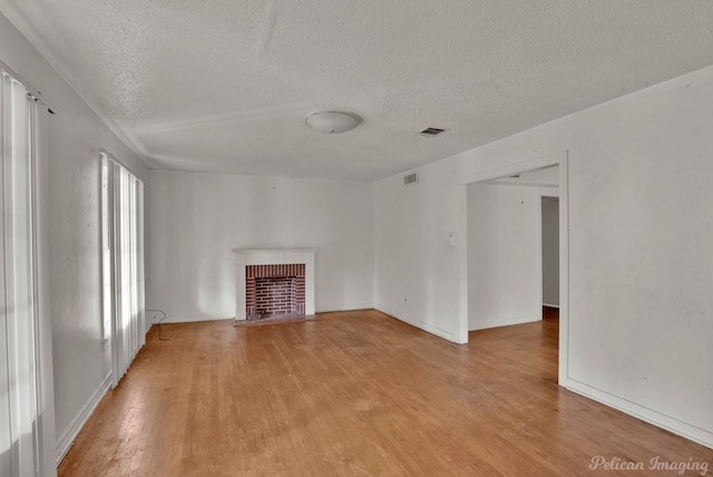 unfurnished living room featuring light wood-type flooring, a fireplace, and a textured ceiling