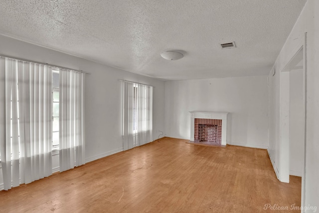 unfurnished living room with a fireplace, light hardwood / wood-style floors, and a textured ceiling