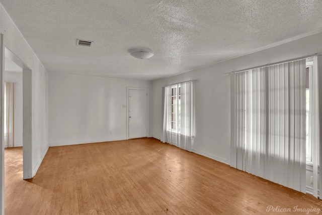 unfurnished room with a textured ceiling and light hardwood / wood-style flooring