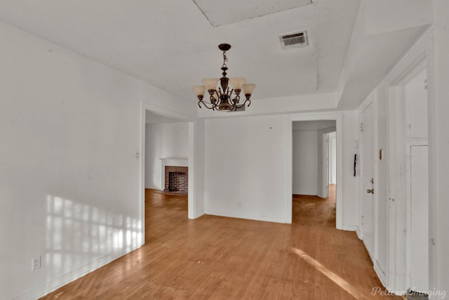 unfurnished dining area featuring a fireplace, wood-type flooring, and a chandelier