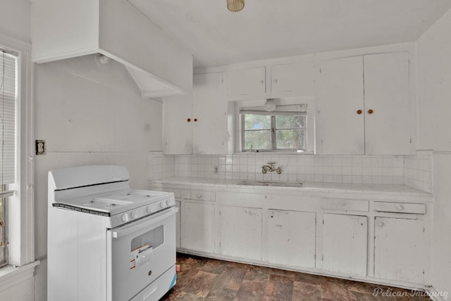 kitchen featuring white range, decorative backsplash, sink, tile counters, and white cabinets