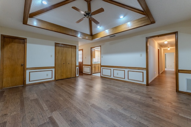 unfurnished room featuring ceiling fan, a raised ceiling, wood-type flooring, and a textured ceiling