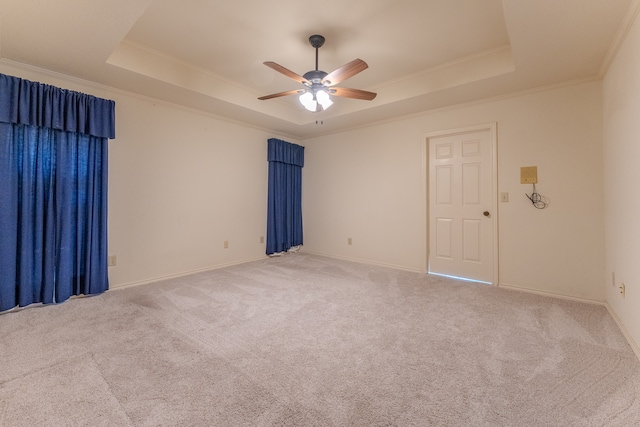 empty room featuring carpet floors, a tray ceiling, ceiling fan, and crown molding