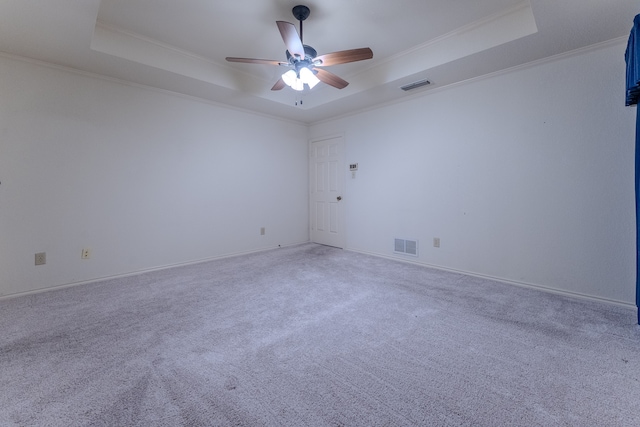 carpeted empty room with ceiling fan, a raised ceiling, and ornamental molding