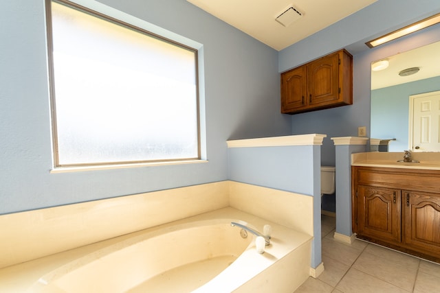 bathroom with tile patterned flooring, vanity, toilet, and a tub to relax in