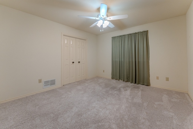 unfurnished bedroom featuring light carpet, a closet, and ceiling fan