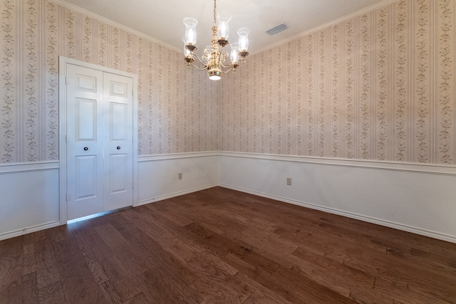 unfurnished dining area featuring ornamental molding, a textured ceiling, an inviting chandelier, and dark wood-type flooring