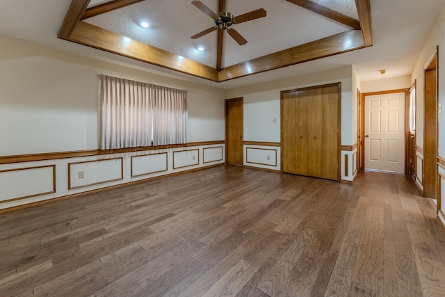 empty room with hardwood / wood-style flooring, ceiling fan, a textured ceiling, and a tray ceiling