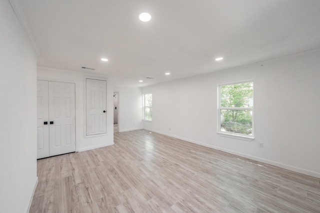 empty room featuring ornamental molding, light hardwood / wood-style floors, and a healthy amount of sunlight