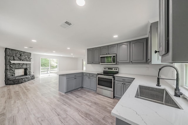 kitchen with stainless steel appliances, sink, gray cabinetry, and light hardwood / wood-style flooring