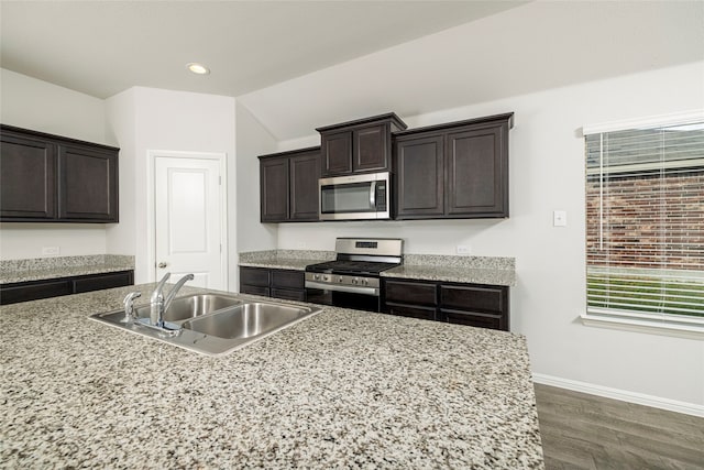 kitchen featuring stainless steel appliances, dark hardwood / wood-style flooring, vaulted ceiling, sink, and dark brown cabinets