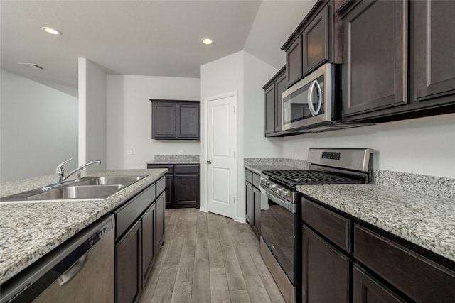 kitchen featuring sink, appliances with stainless steel finishes, light stone countertops, and light hardwood / wood-style flooring