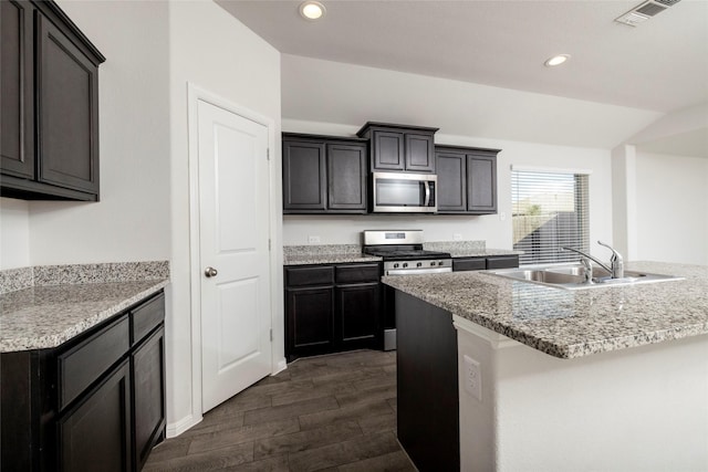 kitchen with stainless steel appliances, dark hardwood / wood-style flooring, a kitchen island with sink, and sink